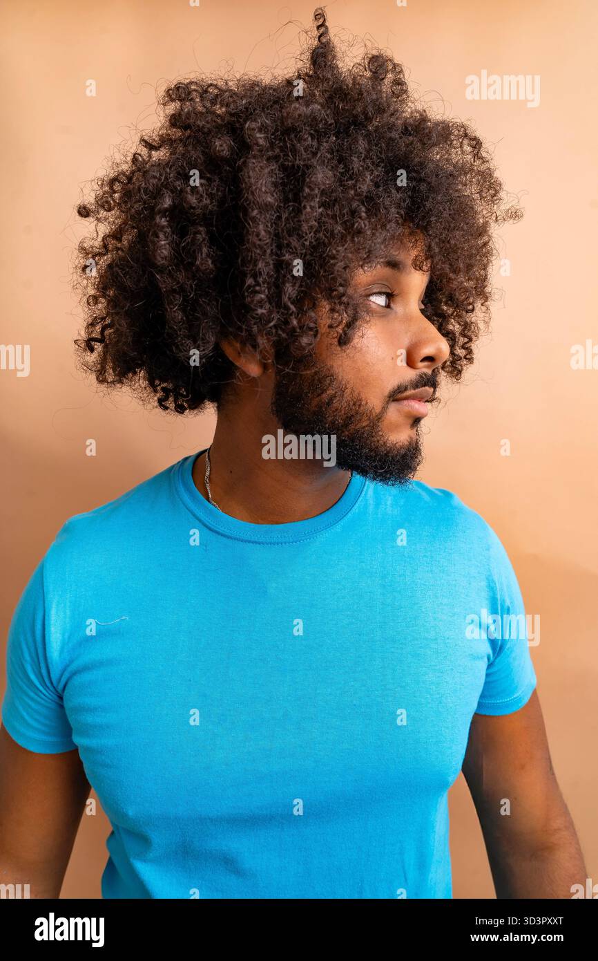 Young man with curly hair looking sideways thoughtfully Stock Photo