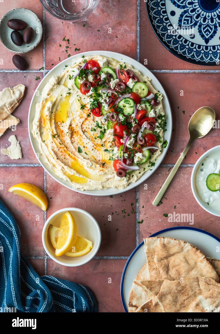 Top view hummus platter with medierranean ingredients and pitas. Stock Photo
