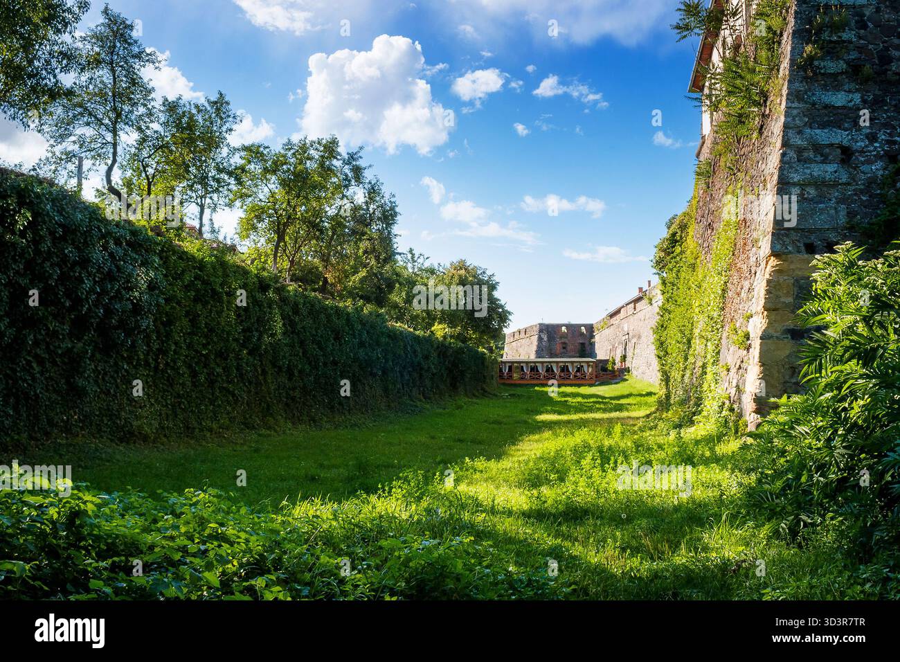 uzhhorod, ukraine - 08 aug 2012: grass in the old castle moat on a sunny afternoon. legendary landmark of transcarpathia under blue sky. medieval stro Stock Photo