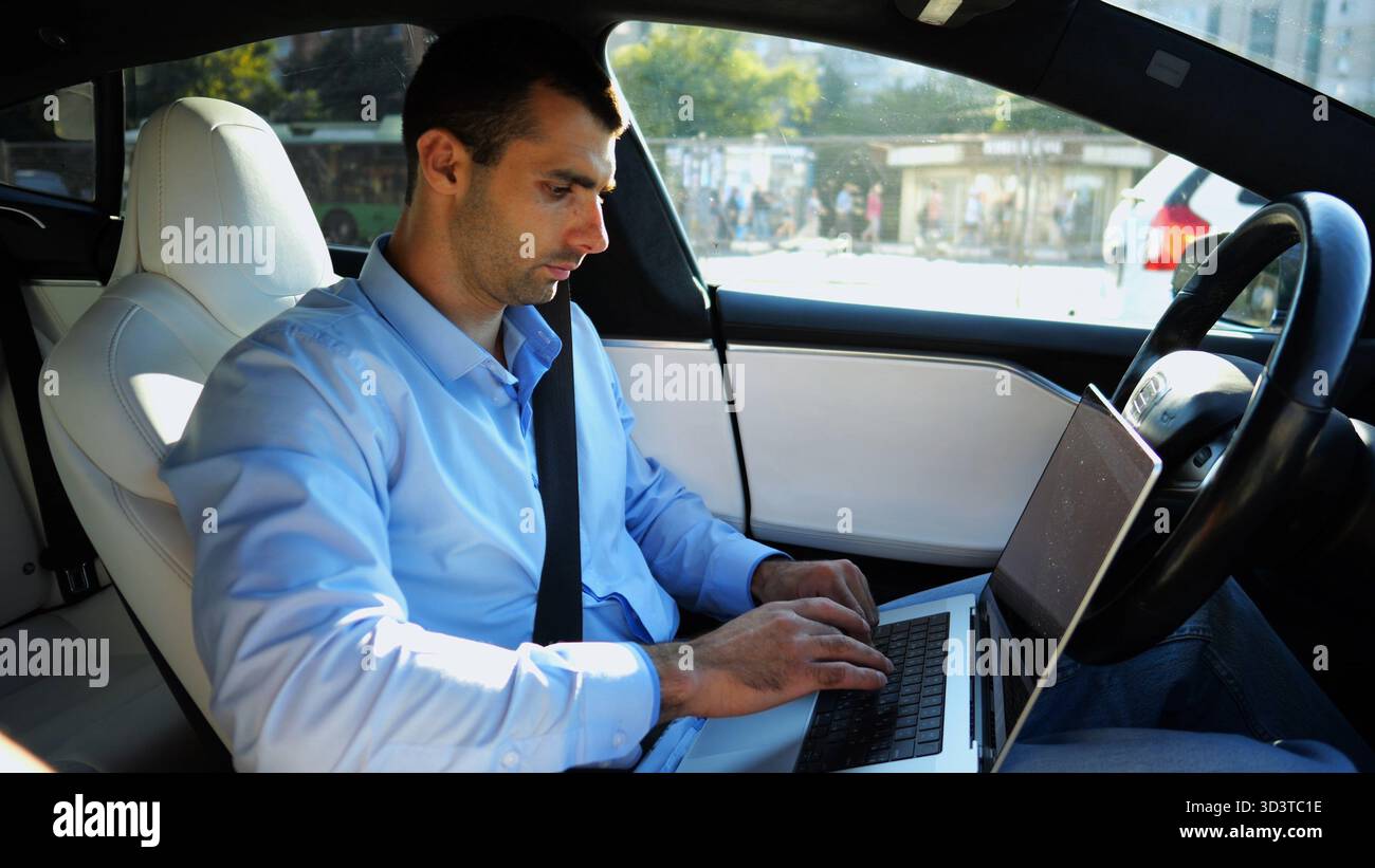 Handsome entrepreneur working on notebook while riding an autonomous ...