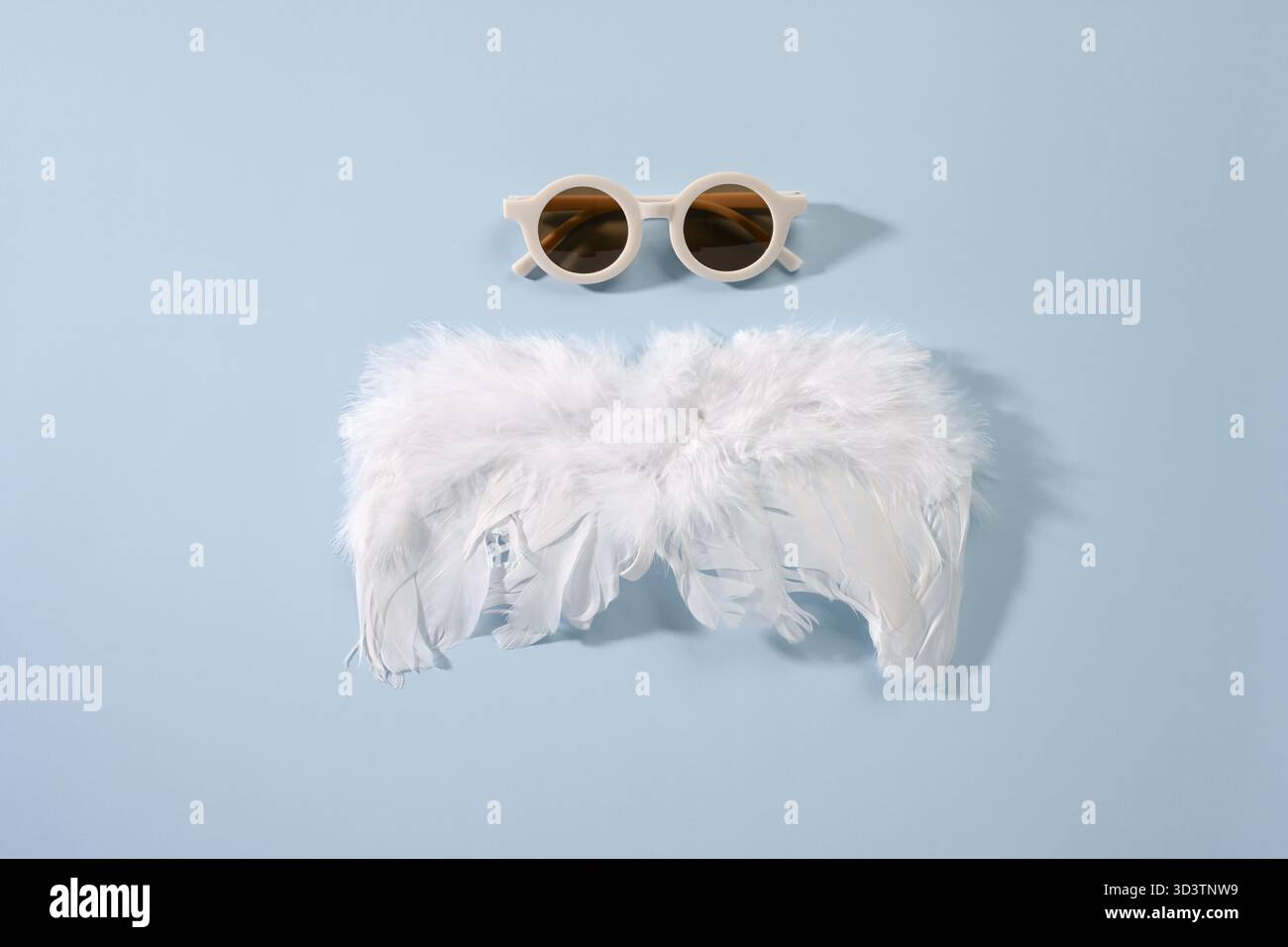 Composition with soft white feathers and brown walnuts on blue background. Stock Photo