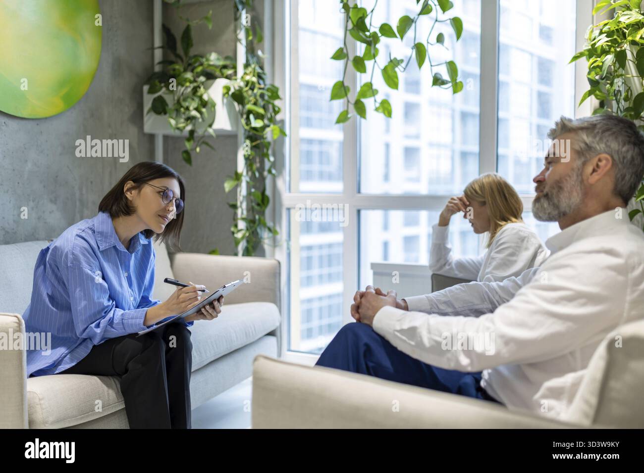 Psycho session. Psychologist having a sessiona with a couple and making notes Stock Photo