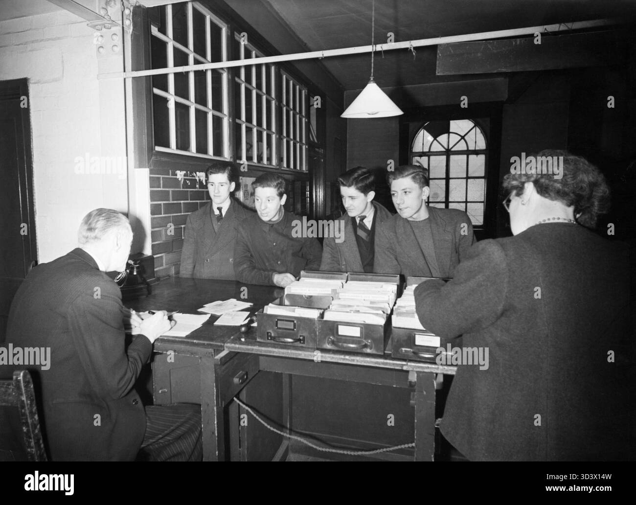 Sixteen Year Olds Register- Teenagers Receive Their Adult Id Cards at the Labour Exchange, London, England, UK, 1945 A group of 16-year-old boys arrive at the Labour Exchange, Islington to register for their adult Identity Cards. Left to right, they are: Roy Clements (draughtsman), Robert Hinch (cartage contractor's workman), James Beck (studying to be a commercial artist) and James Pickering (junior clerk). Pickering has volunteered for the Merchant Navy, and is at the Exchange not to register for his ID card, but to receive final permission to leave his present job. According to the original Stock Photo