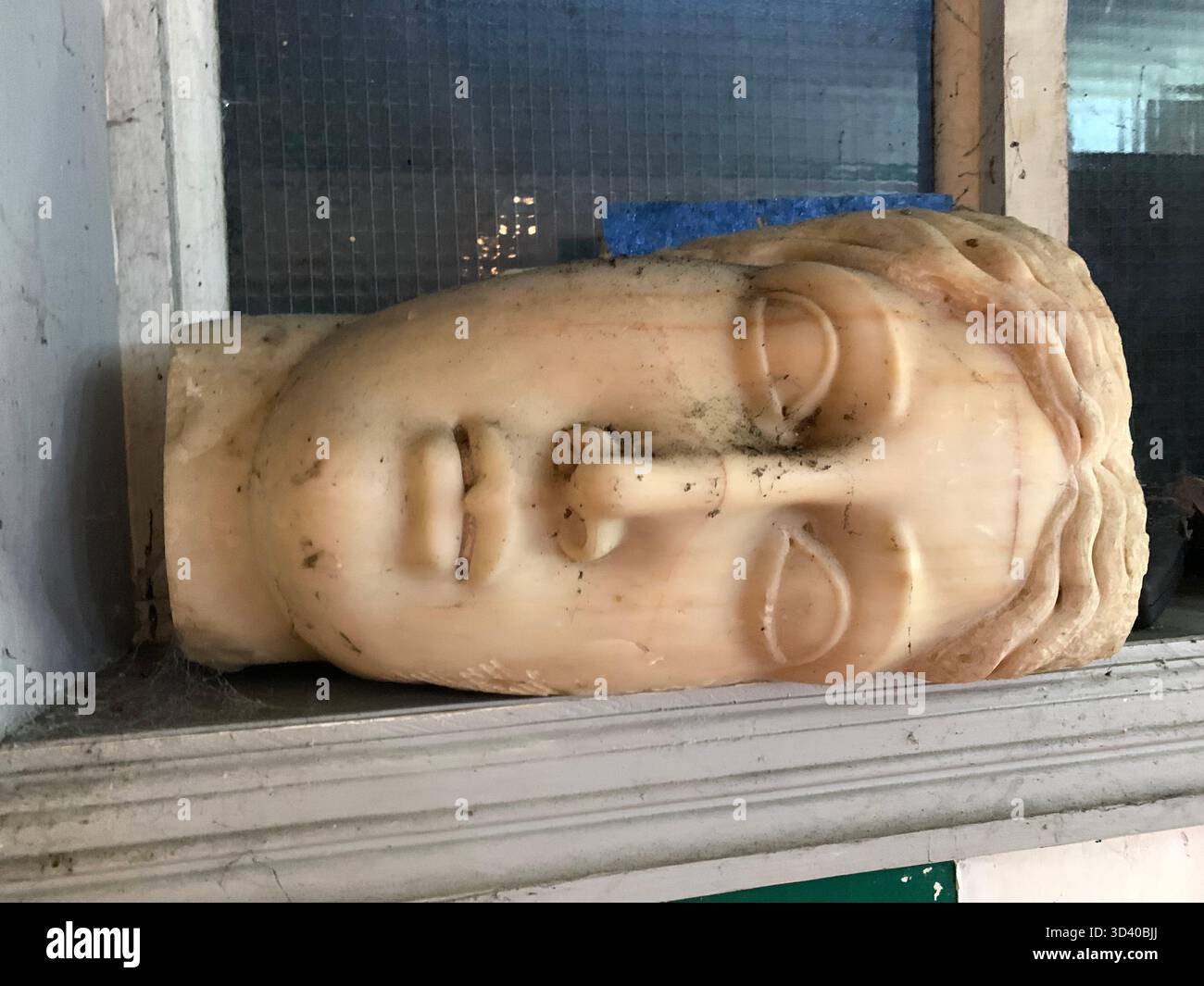 Sculpture head in classical style ancient Greek or Roman art serene expression closed eyes stylized hair idealized figure deity or a philosopher marble - Smartphone Captured Stock Image