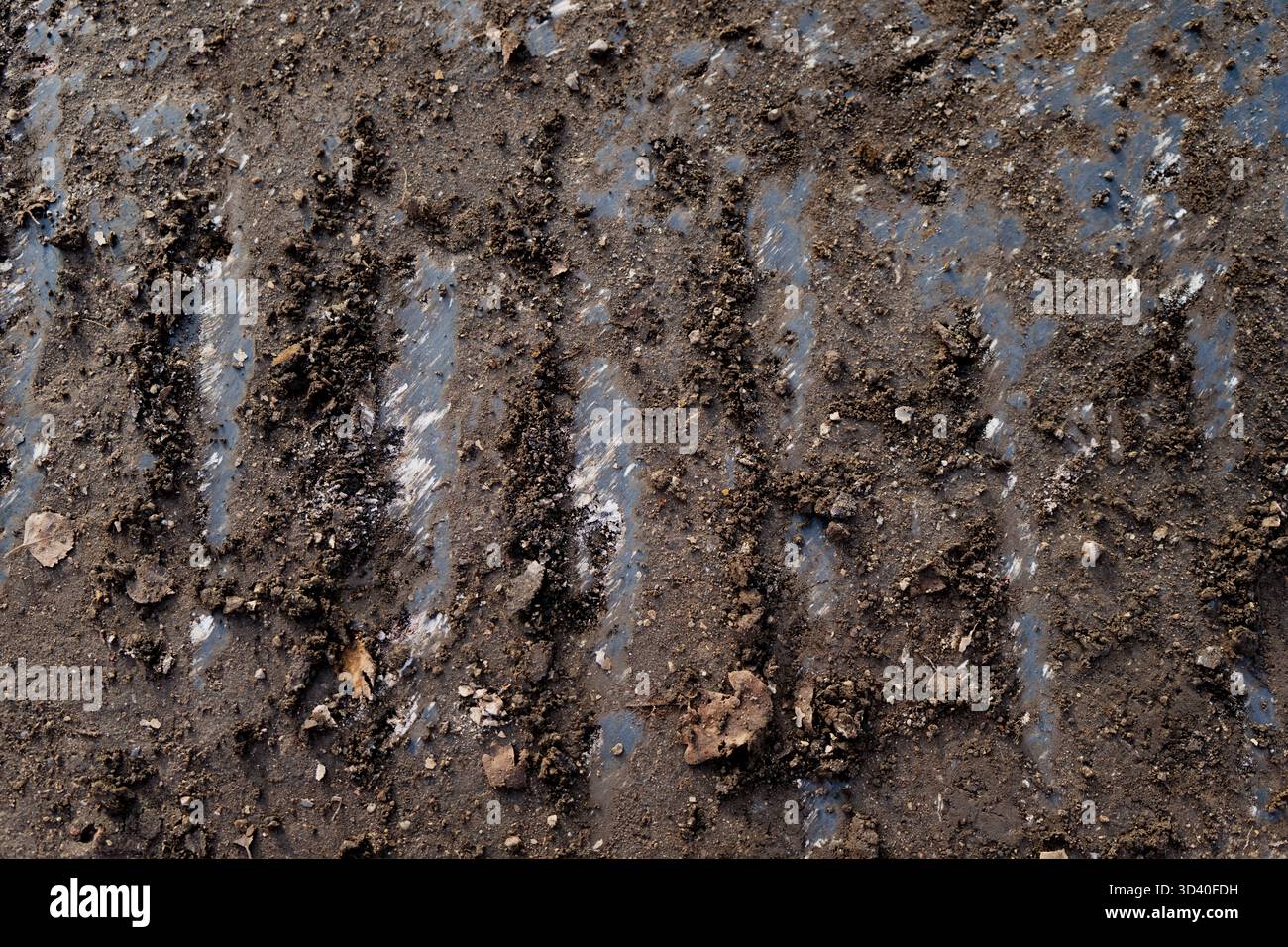 Muddy ground with visible crawler tread imprints and soil compaction ...