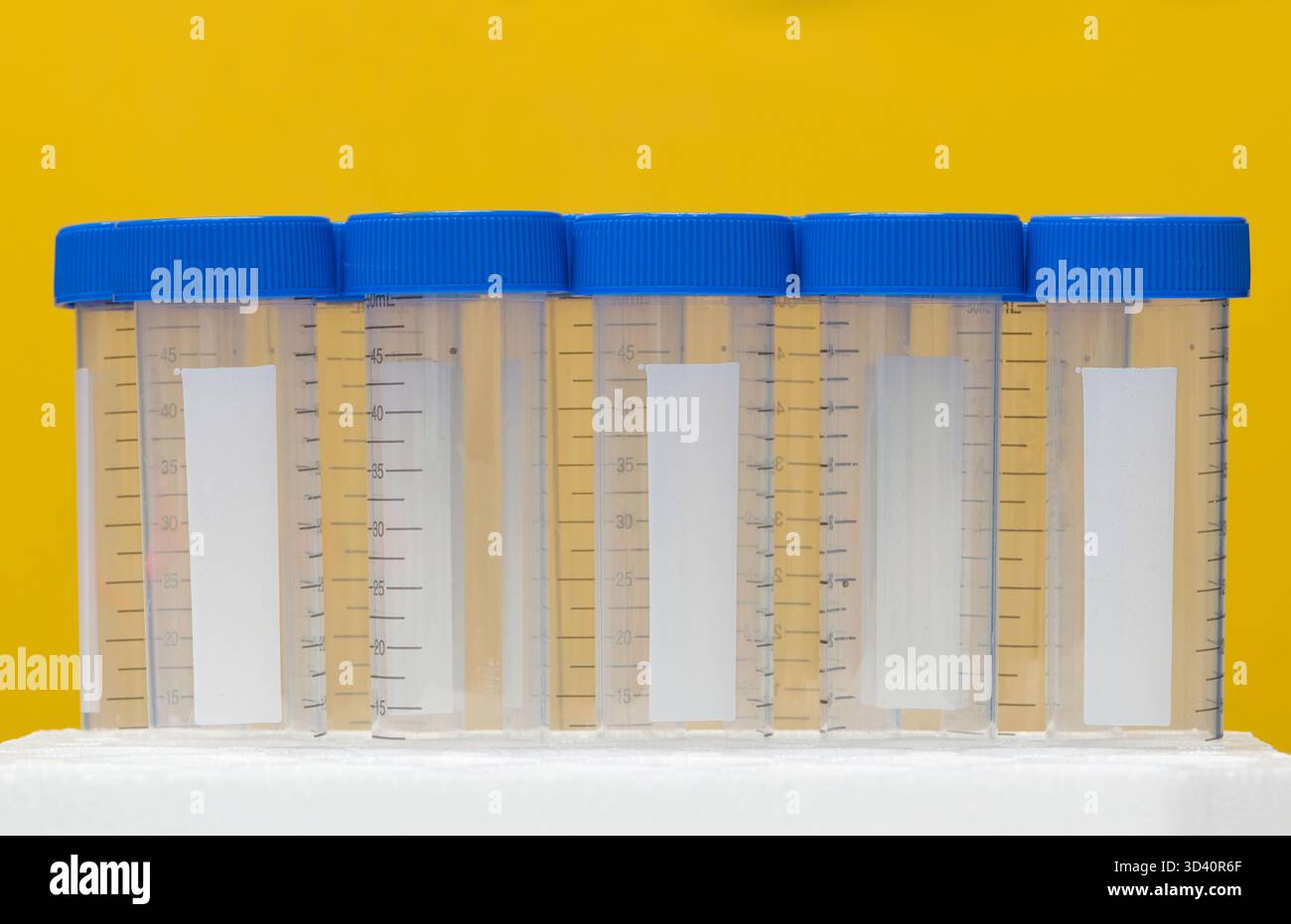 Plastic test tubes empty bottle vials milliliter measurement with caps on yellow background. Stock Photo