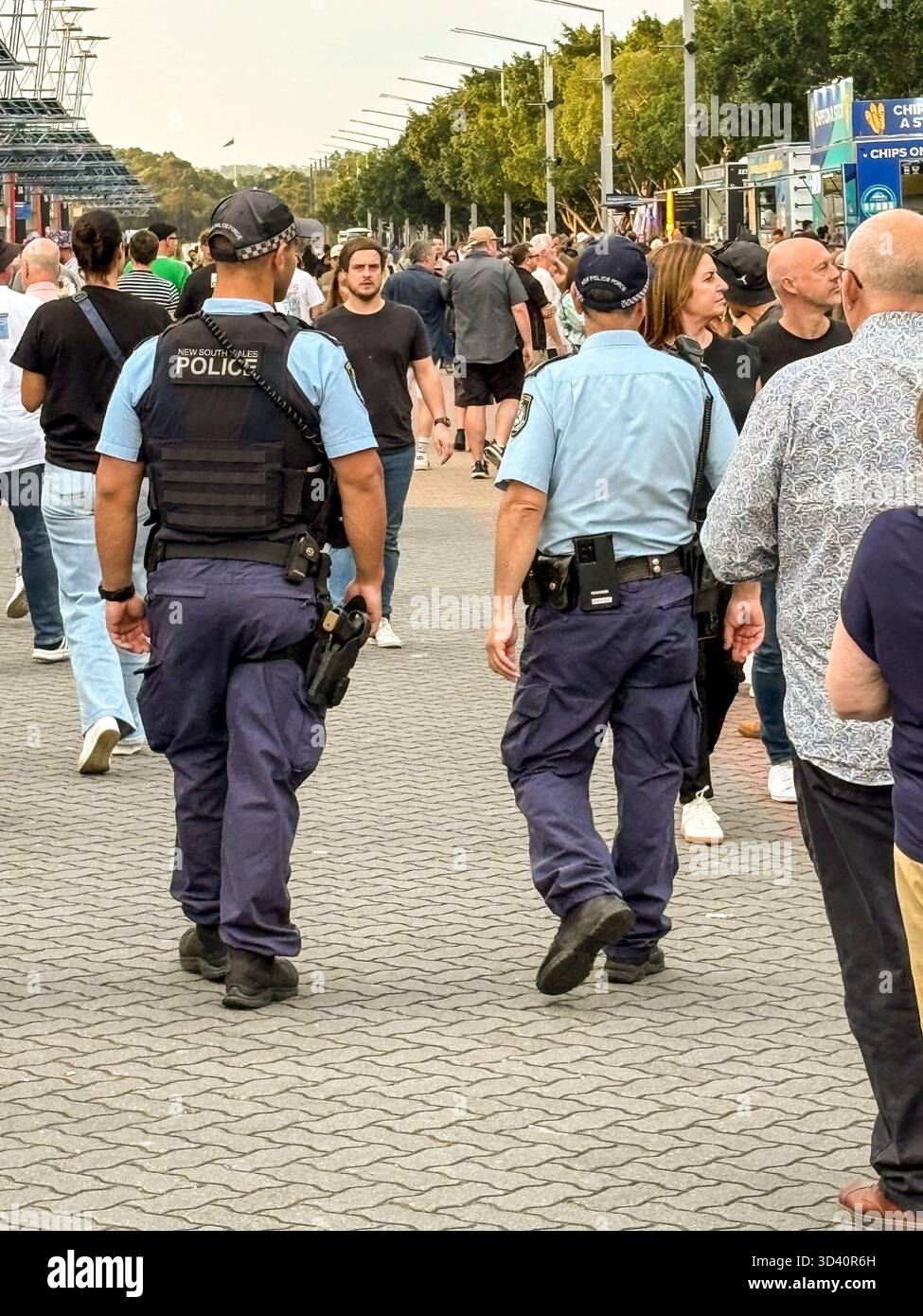 Australian police officers, two male New South Wales NSW policemen patrol the crowds outside the Accor  Stadium before the Oasis Live 25 concert - Smartphone Captured Stock Image