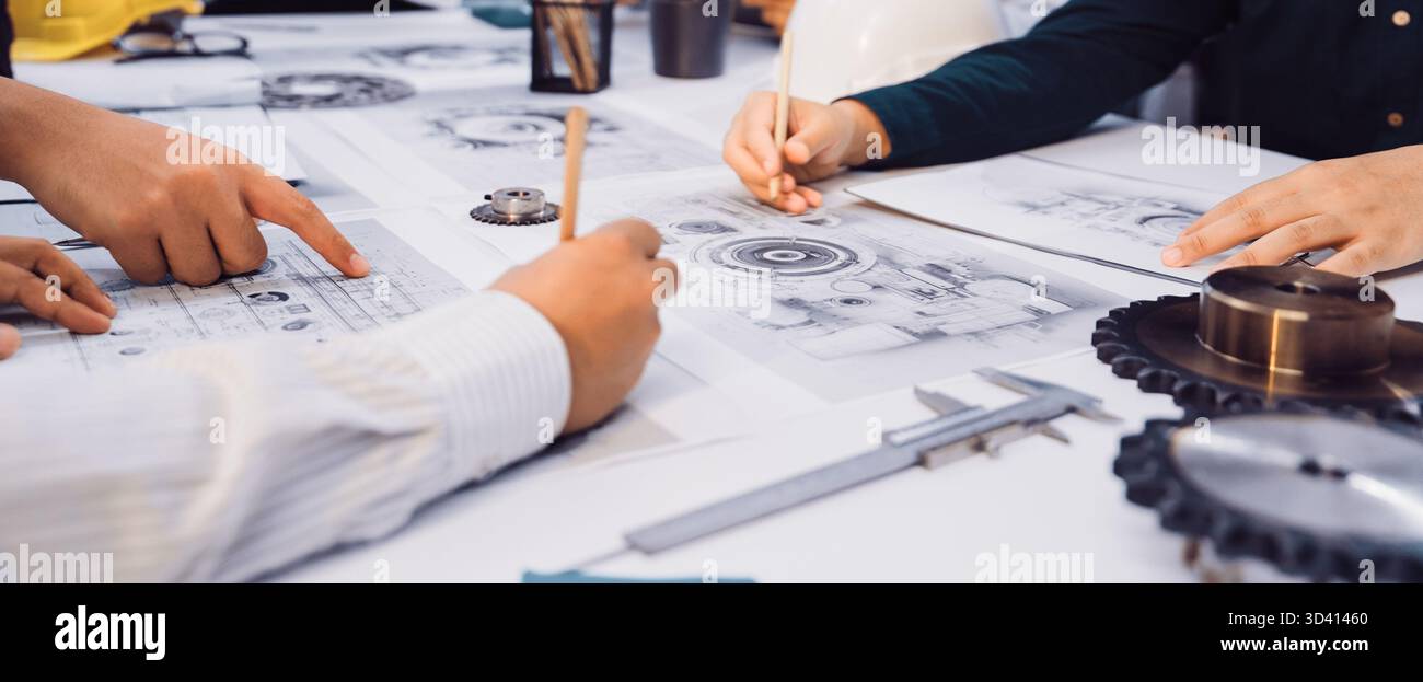 A dynamic scene showcasing a collaborative engineering meeting where hands interact over technical drawings and tools. Professionals engage in active Stock Photo