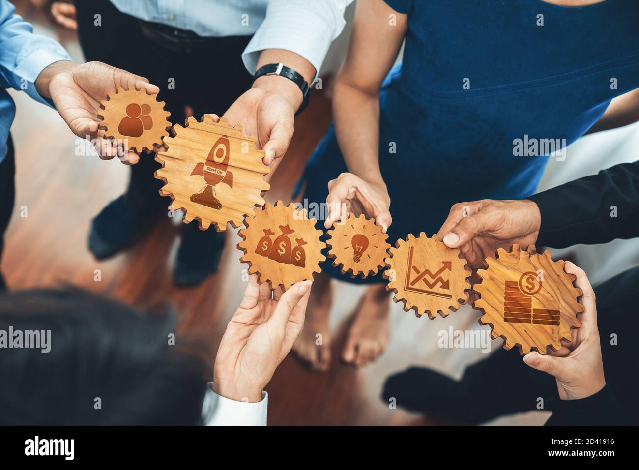 A diverse team of professionals engages in collaborative strategy sessions, using wooden gears as metaphors for innovation and growth in a modern Stock Photo