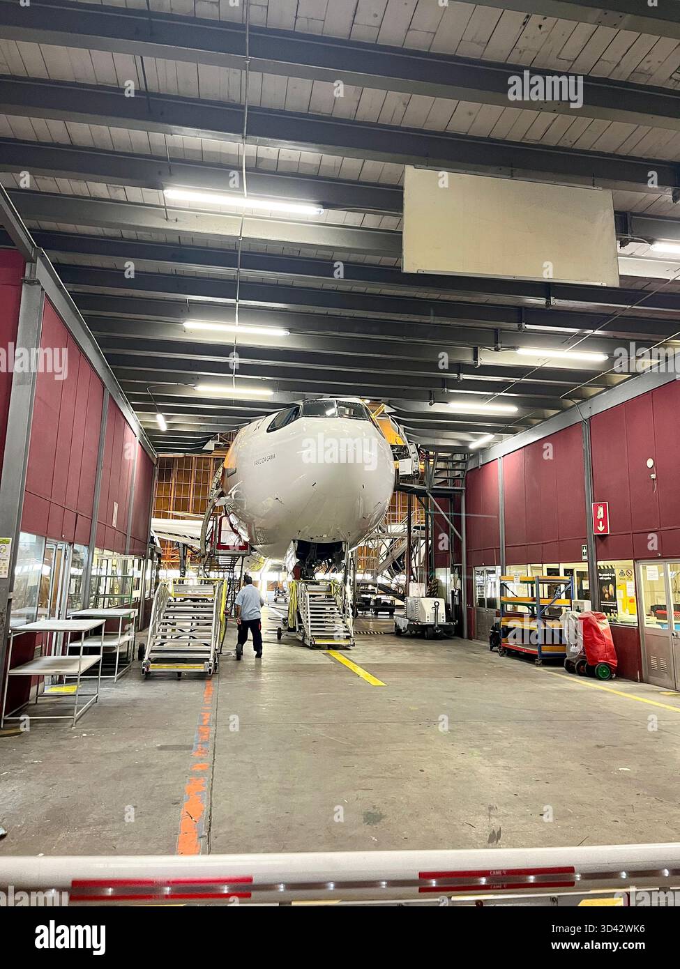 TAP Air Portugal aircraft undergoing maintenance inside an engineering hangar with platforms and industrial equipment. - Smartphone Captured Stock Image