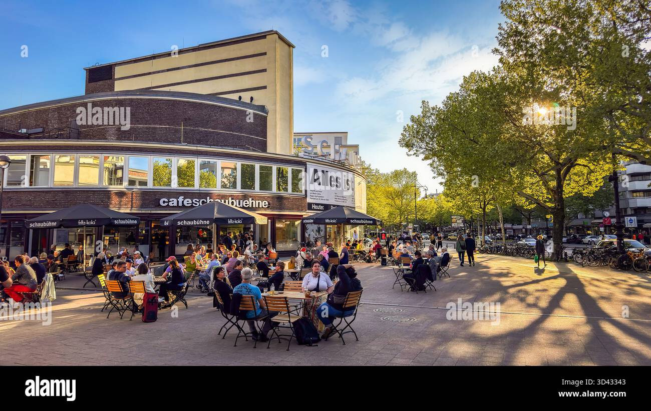 Berlin, Deutschland – Menschen sitzen auf der Terrasse des Schaubühne-Cafés im warmen Nachmittagslicht am Kurfürstendamm Stock Photo