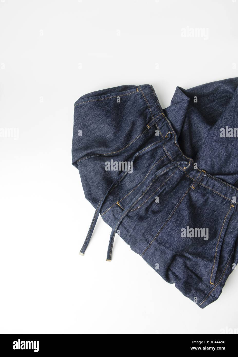Denim jeans randomly stacked on white background, copy space Stock Photo