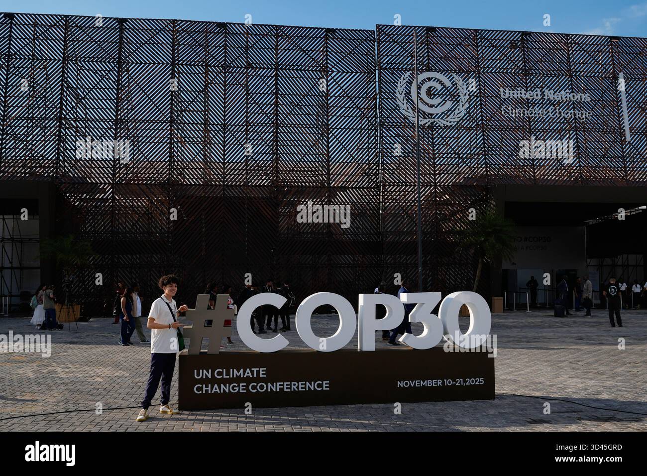 A person poses for a photo with a sign for the COP30 U.N. Climate ...