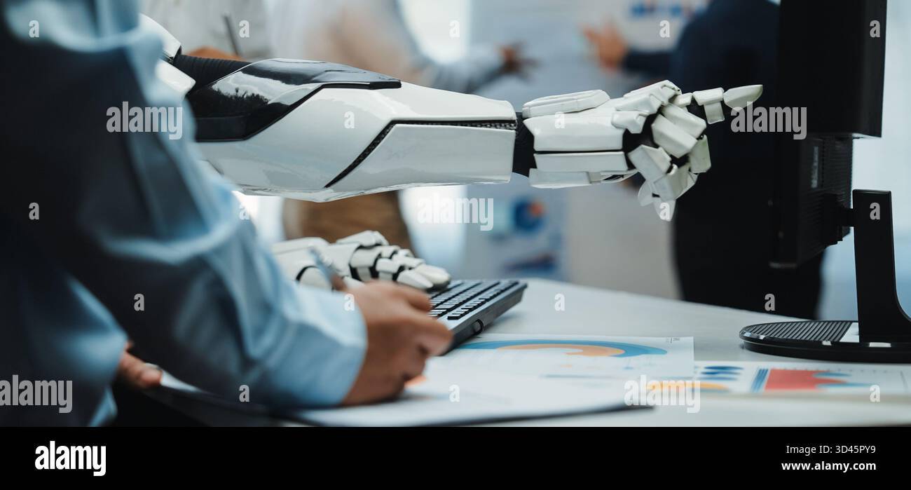 A close-up view of a robotic arm interacting with a computer, illustrating the seamless integration of advanced technology in modern work environments Stock Photo