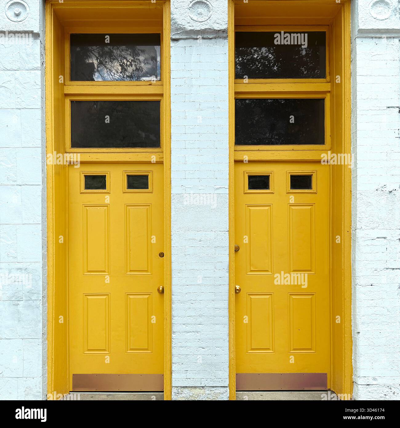 Twin yellow doors framed by white brick, capturing Chicago’s architectural symmetry and vibrant color in a classic urban facade - Smartphone Captured Stock Image