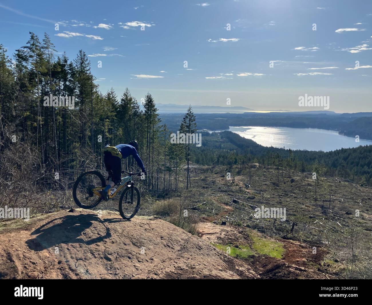 A mountain biker on a rocky trail at Forbidden Plateau overlooking Comox Lake in the Comox Valley on Vancouver Island, British Columbia, Canada. - Smartphone Captured Stock Image