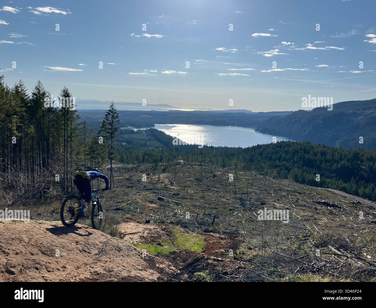 A mountain biker on a rocky trail at Forbidden Plateau overlooking Comox Lake in the Comox Valley on Vancouver Island, British Columbia, Canada. - Smartphone Captured Stock Image