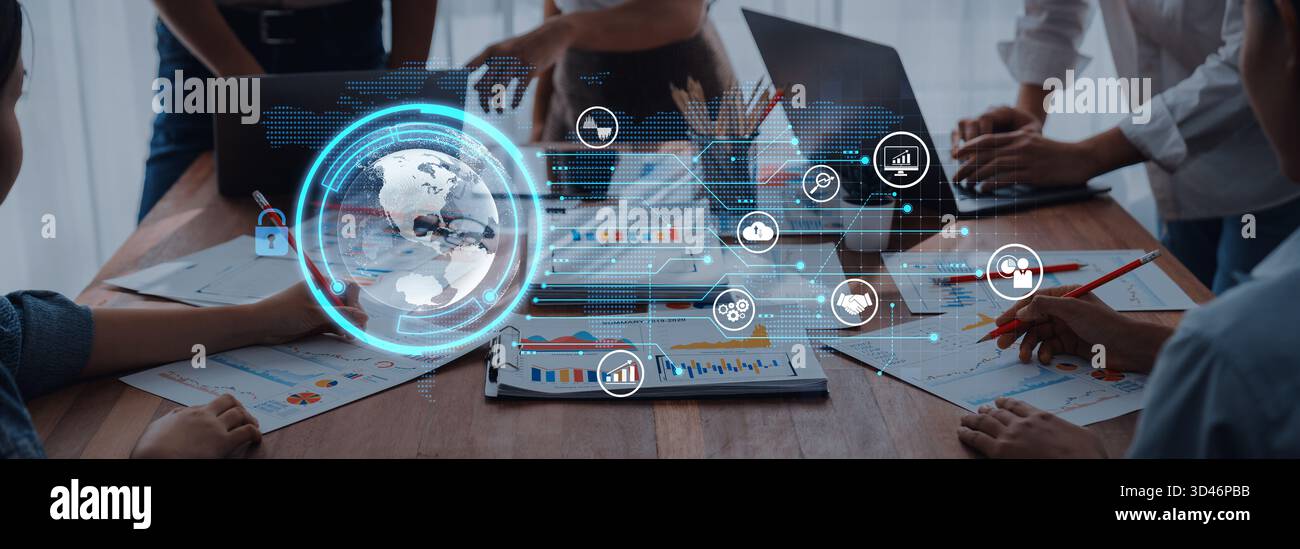 A dynamic business meeting with professionals collaborating around laptops and tables, featuring digital data visualization tools and global analytics Stock Photo