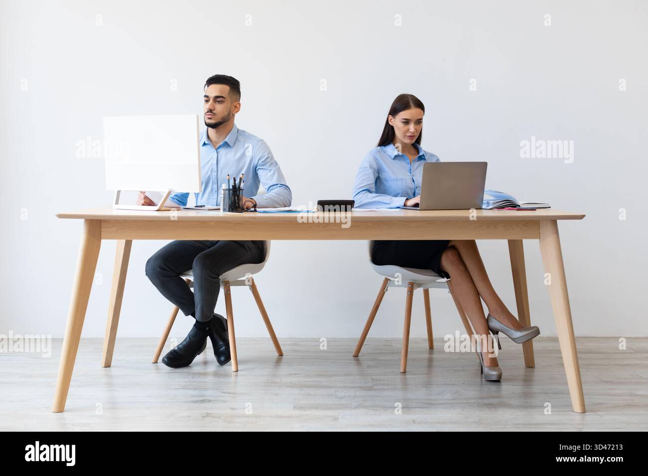 Focused Colleagues Collaborate in a Modern Office Setting While Using Laptops Stock Photo