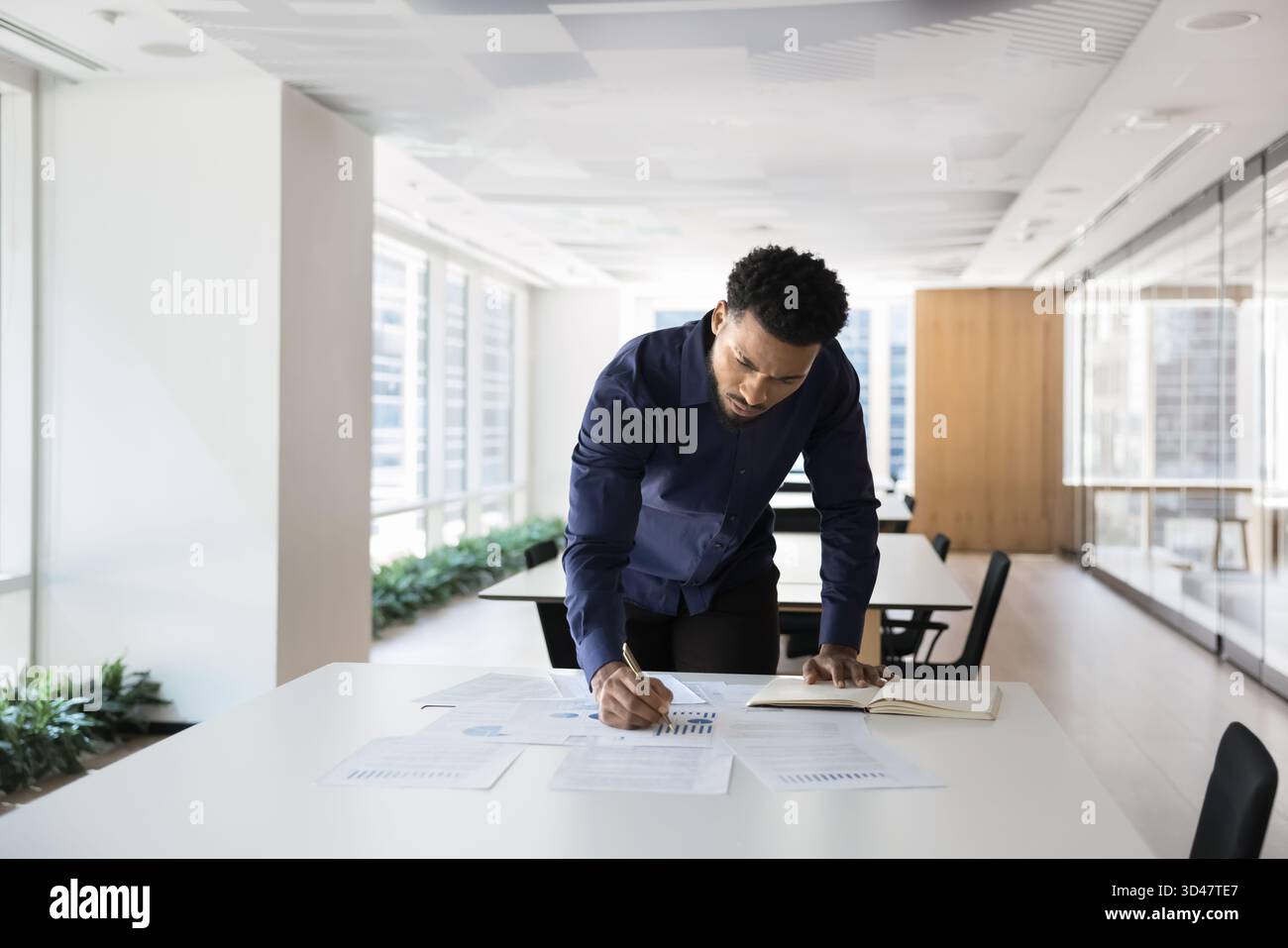 Concentrated young African man study statistic documents on office table Stock Photo