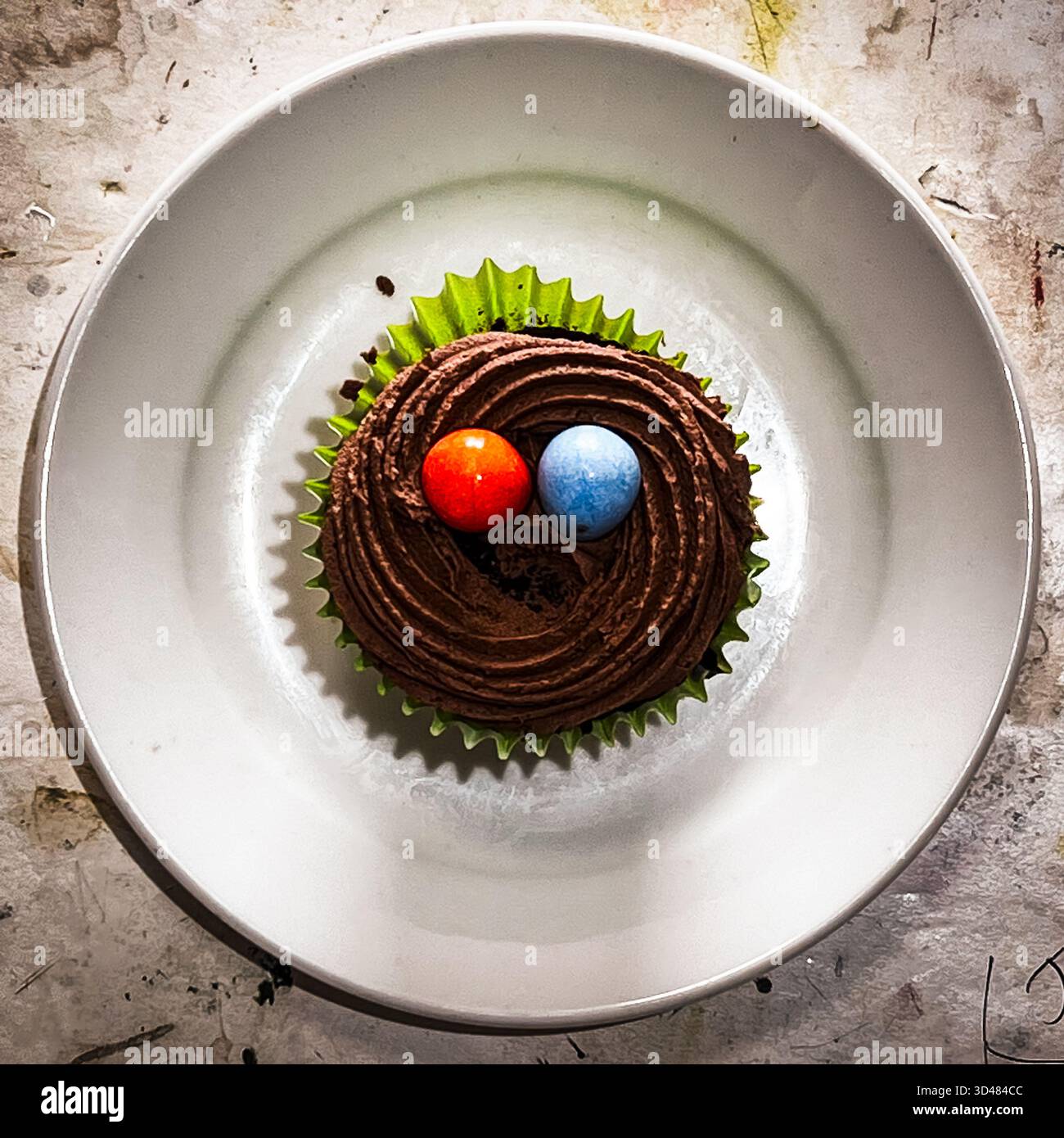 A cupcake with chocolate coloured icing and 2 candy eggs - Smartphone Captured Stock Image
