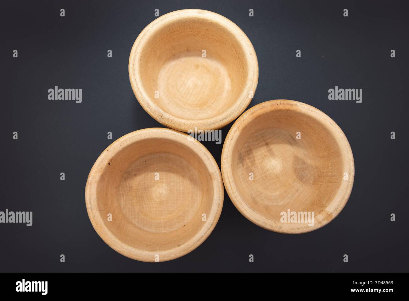 Three small wooden bowls on dark background for kitchen and cooking use Stock Photo