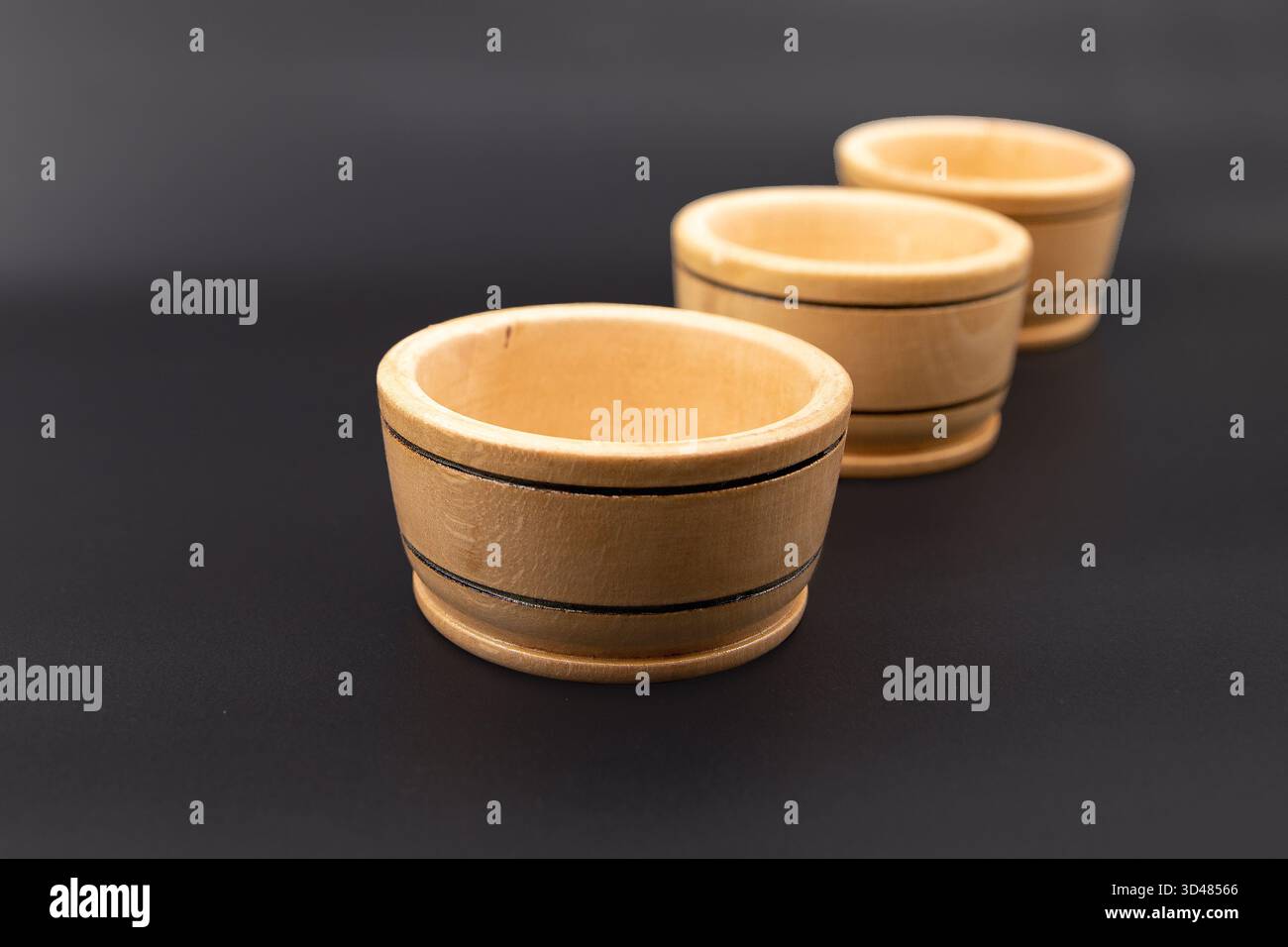 Three small wooden bowls on dark background for kitchen and cooking use Stock Photo