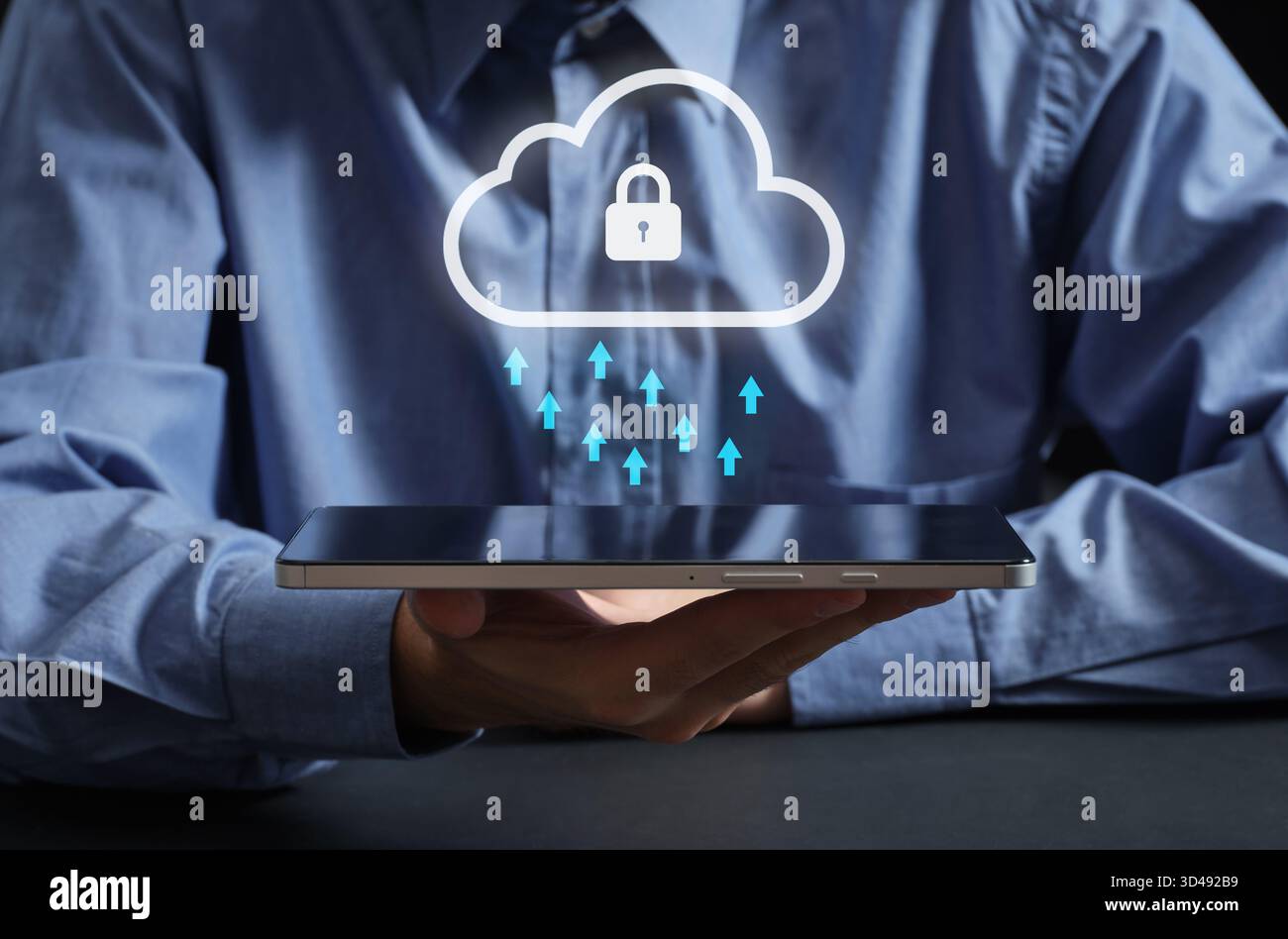 Person holding a tablet displaying a secured cloud icon with arrows symbolizing data upload, representing secure cloud computing Stock Photo