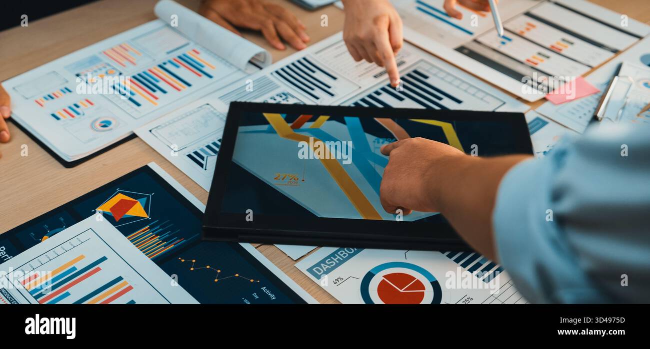 A diverse team collaborates over charts and digital tools during a ...