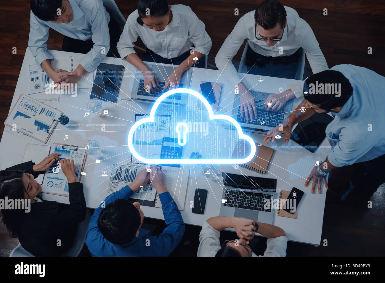 A diverse team collaborates on cloud security solutions within a modern office setting, utilizing laptops and engaging in innovative data sharing and Stock Photo
