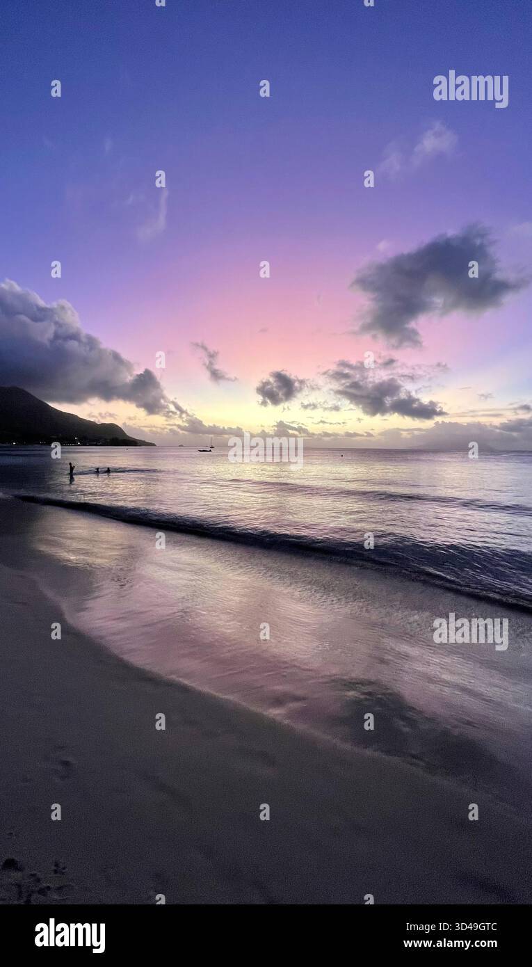 Tropical beach at sunset in Seychelles with purple sky and calm sea, a peaceful seascape full of color and serenity. - Smartphone Captured Stock Image
