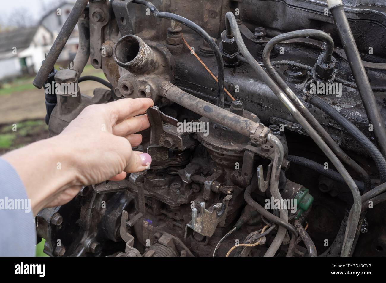 Hand inspecting a dirty engine component on an old vehicle, showing ...
