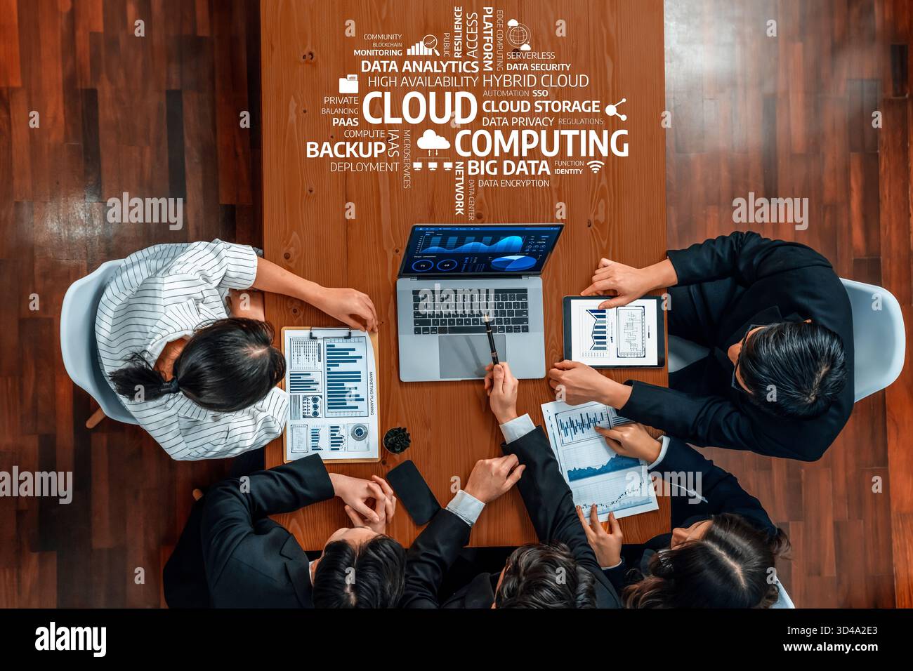 A diverse team meets around a conference table to discuss cloud computing strategies using data analytics, showcasing modern technology and Stock Photo