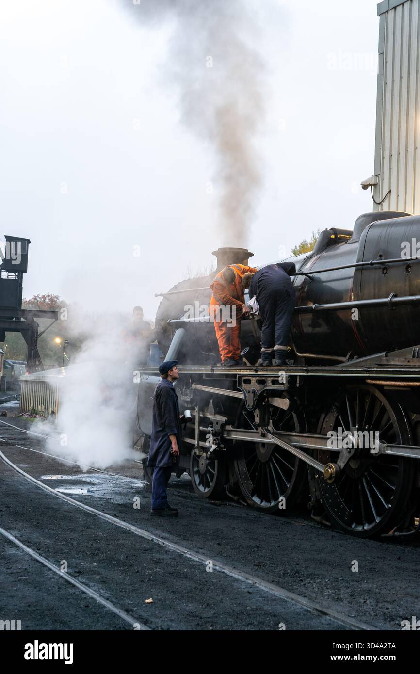 Steam locomotive maintenance crew working on engine at Grosmont station ...