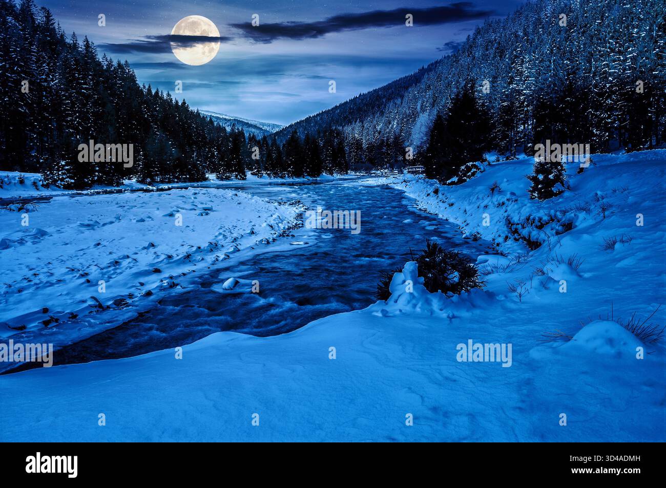 frozen mountain river among spruce forest at night. snow on the ground in full moon light. countryside valley in winter. background for investment or Stock Photo