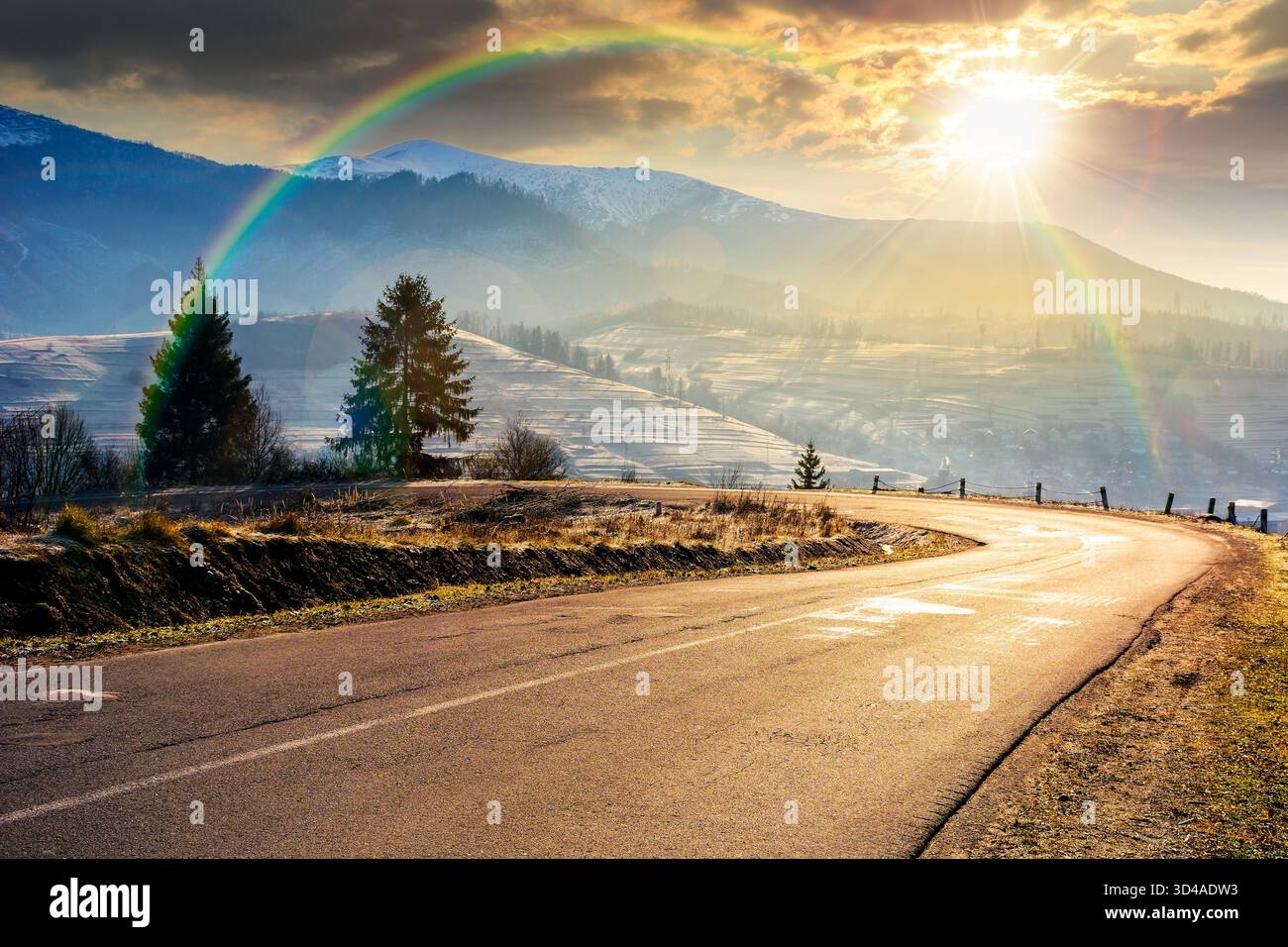 country road in mountains at sunset. beautiful countryside landscape in late autumn. fir trees on the roadside in evening light. scenic view of blue s Stock Photo