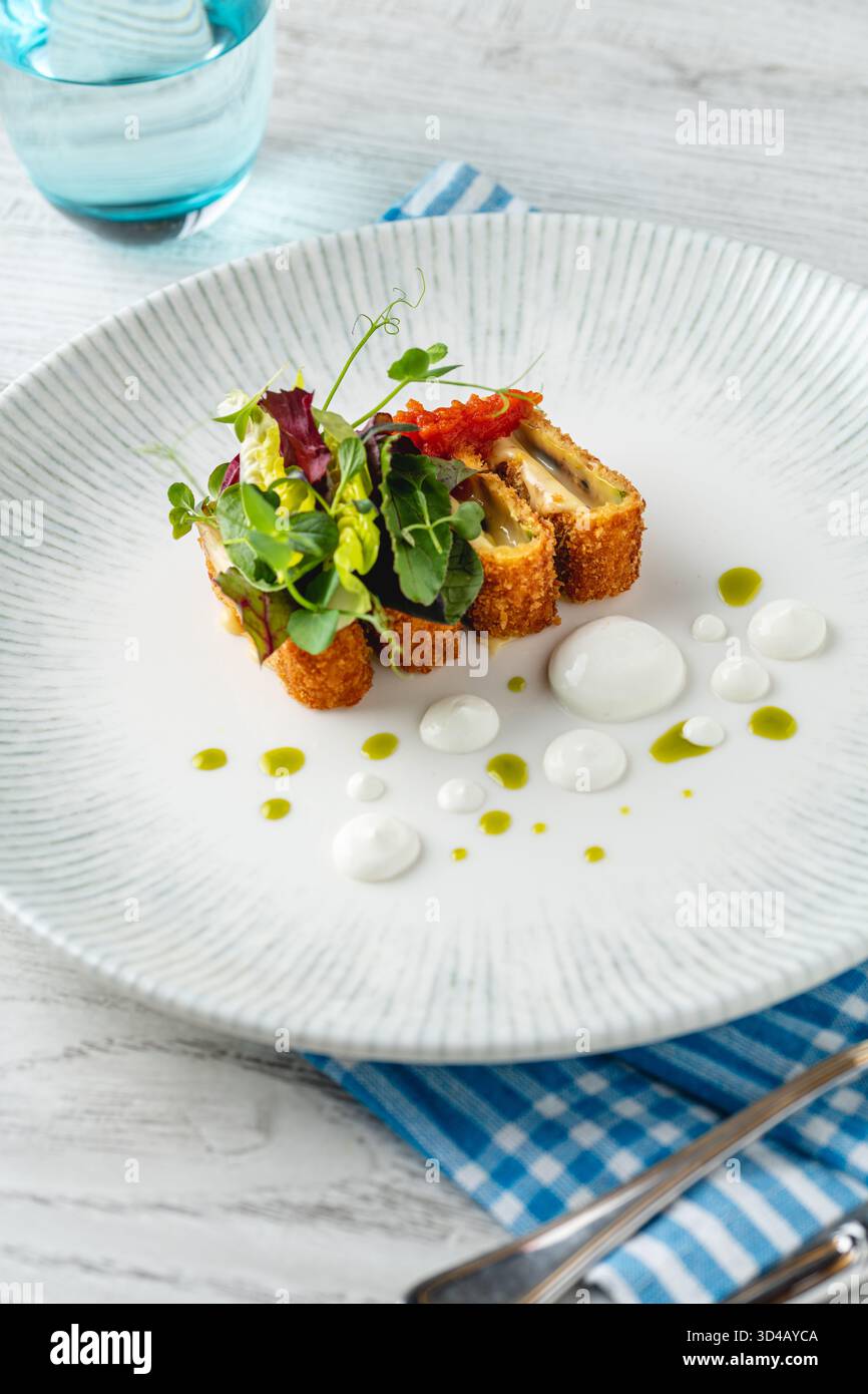 Crispy fish roulade with greens and white sauce drops Stock Photo - Alamy