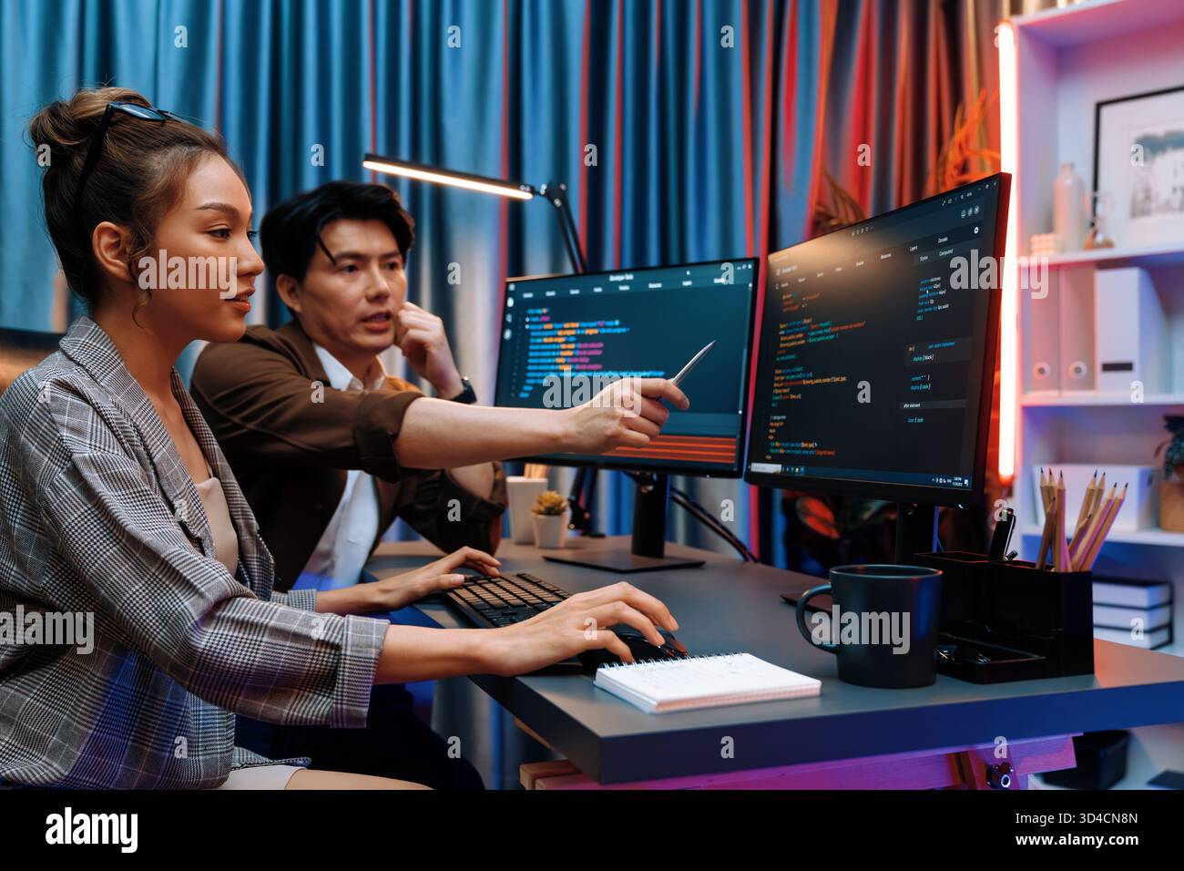 IT developers discussing with point to intelligent website development coder system running data online two screens information technology at neon Stock Photo