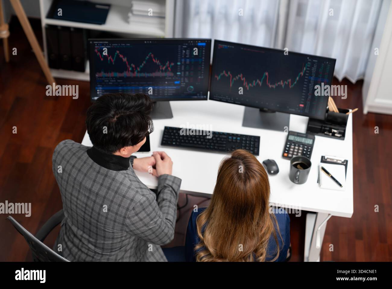 Top image view of analyzing successful Asian businesswoman looking at dynamic stock exchange data screen with businessman partner pointing value rate Stock Photo