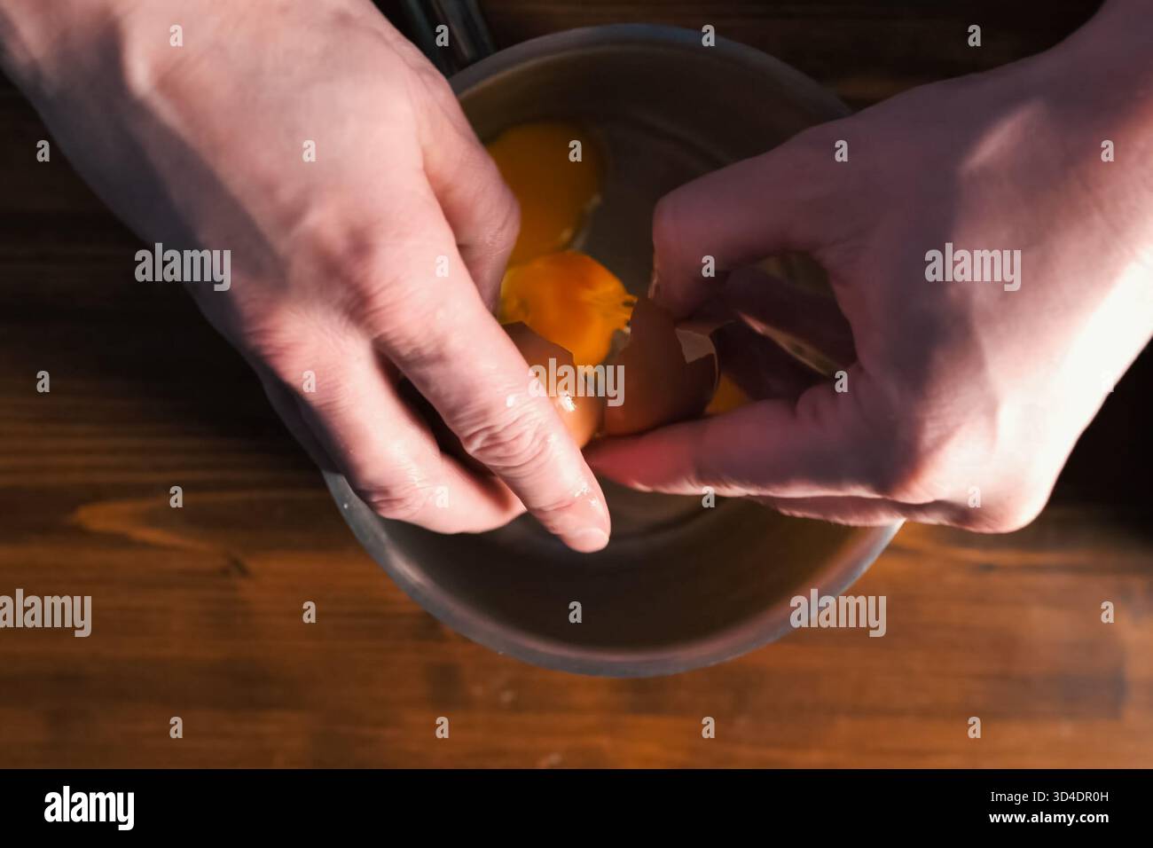 Breaking eggs in a pot, raw eggs for beating. Stock Photo