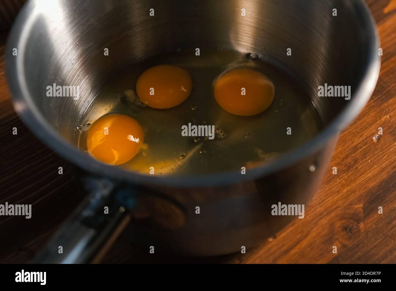 Breaking eggs in a pot, raw eggs for beating. Stock Photo