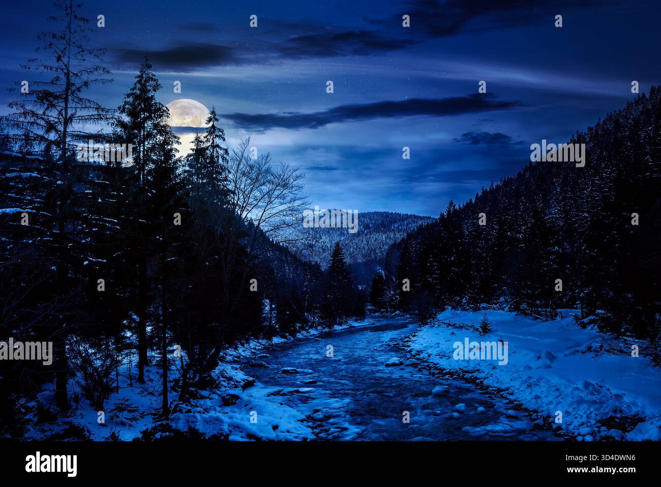 freezing river winding among coniferous forest at night. snow on the ground in countryside valley in full moon light. background for investment or abs Stock Photo