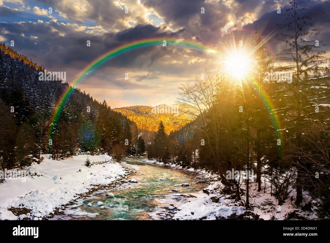 freezing river winding among coniferous forest at sunset. snow on the ground in countryside valley in evening light. storytelling image under the rain Stock Photo