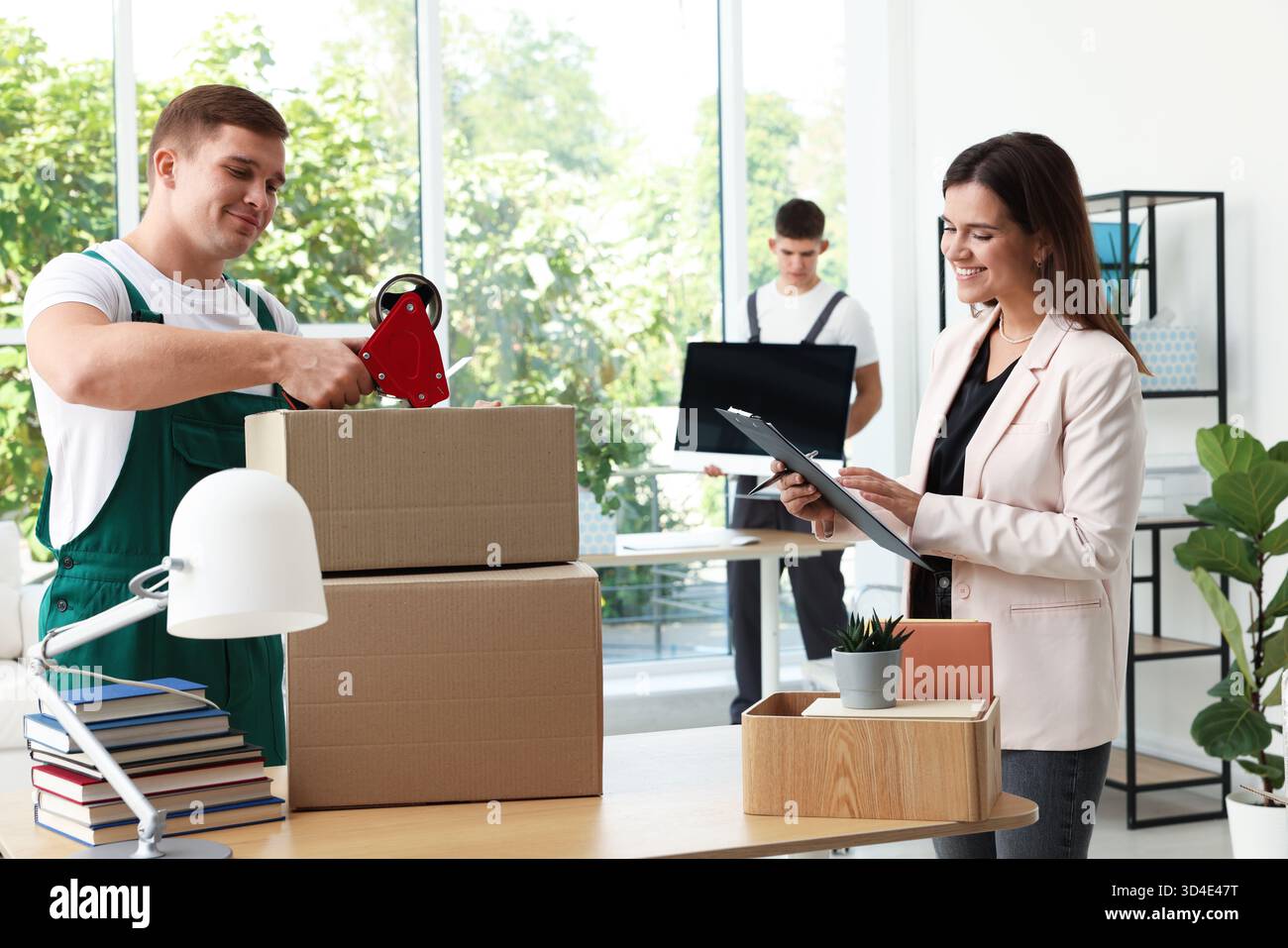 Moving day. Group of workers packing different belongings into boxes in ...
