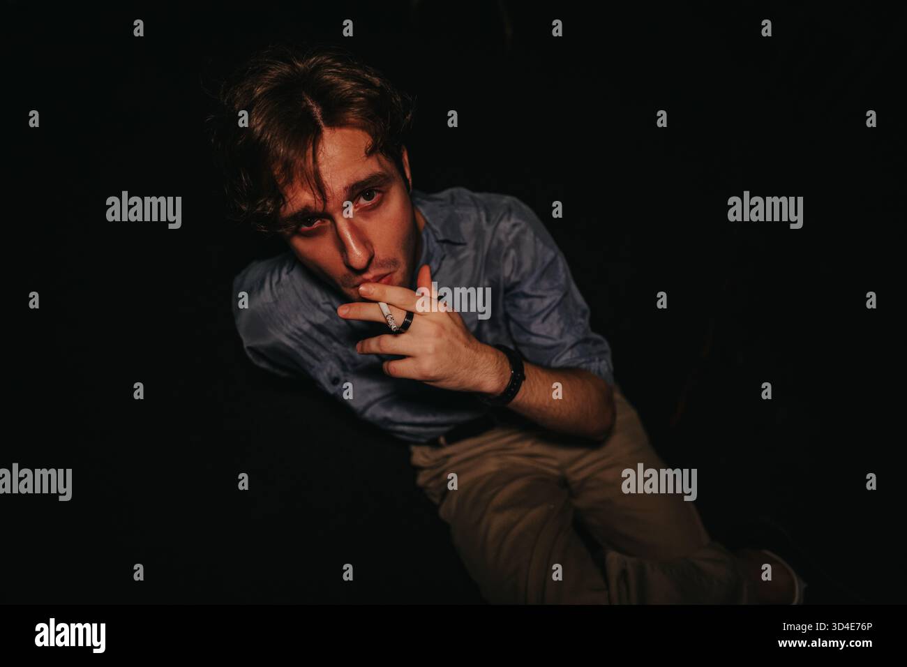 casual cigarette smoking Young man smoking a cigarette in a dark studio, moody casual portrait Stock  Photo