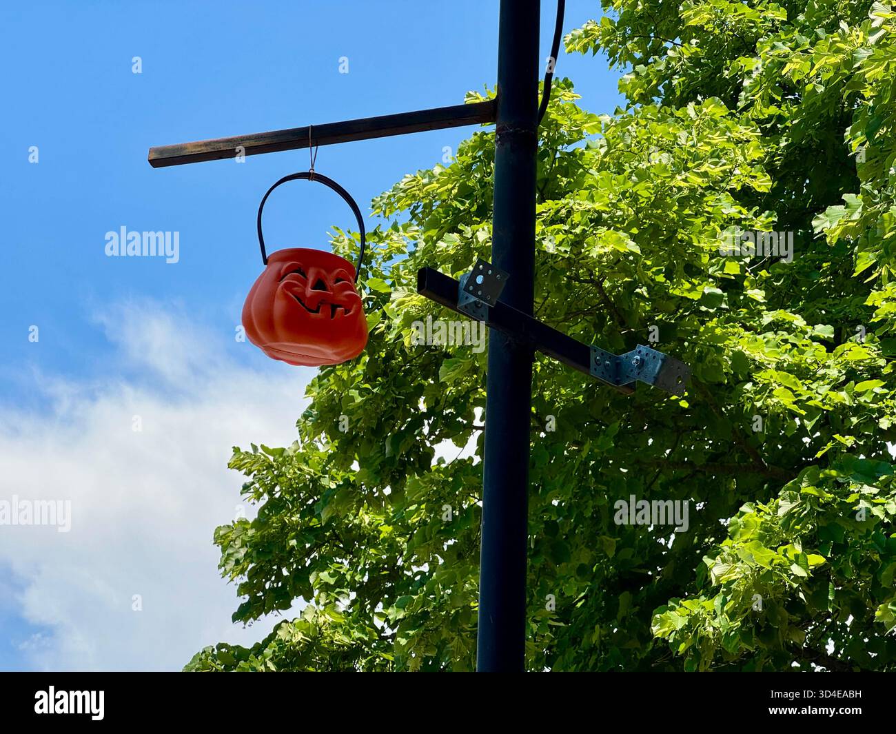 Red lantern-style street lamp mounted on a metal pole in front of a modern glass building and green foliage in Puerto Madero, Buenos Aires, Argentina. - Smartphone Captured Stock Image