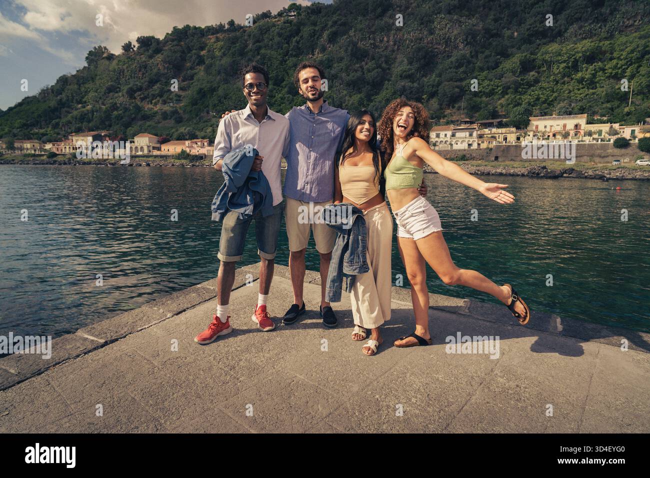 Four friends enjoy a sunny afternoon by the water's edge in a beautiful ...