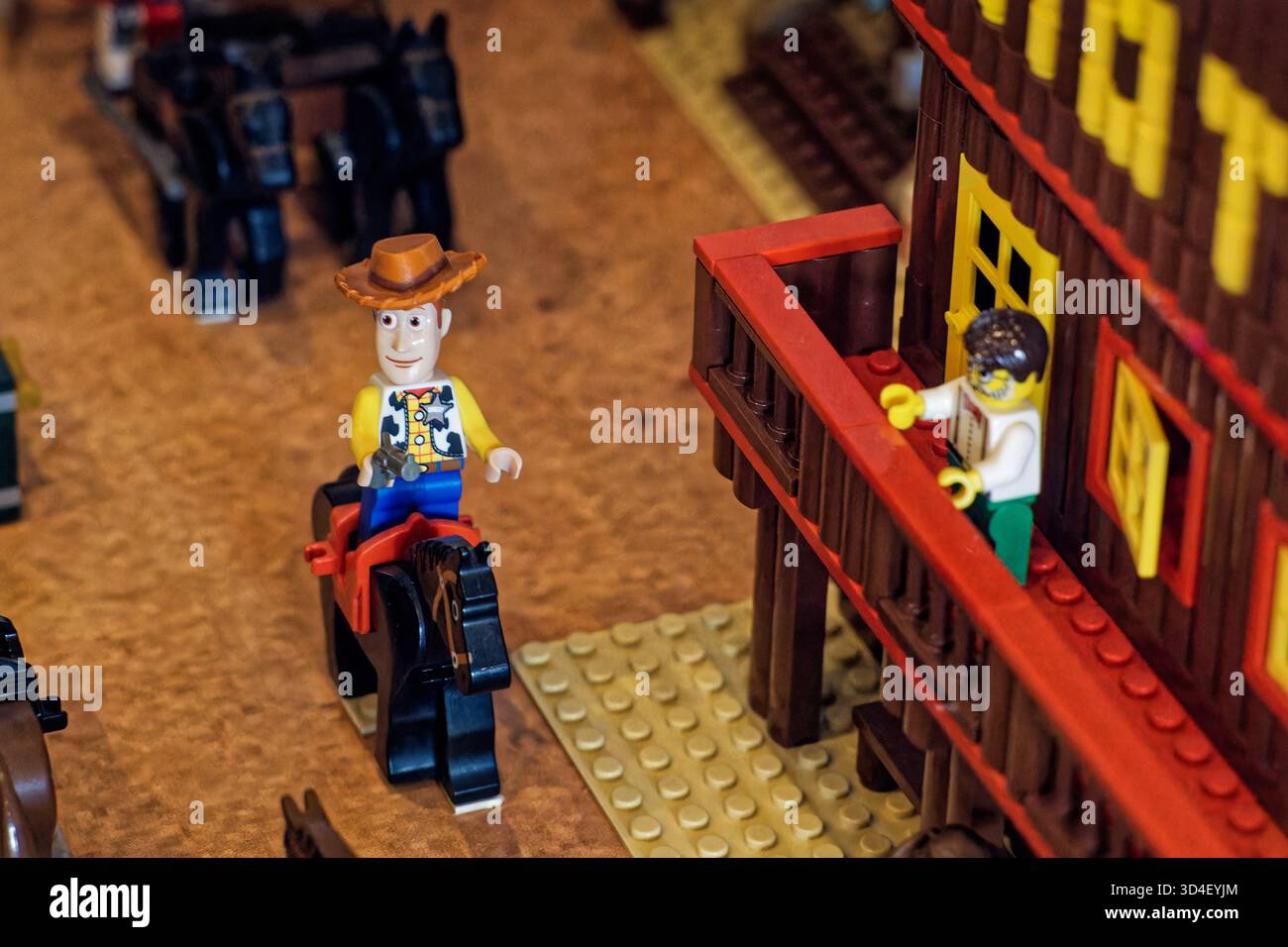 LEGO Woody the cowboy minifigure from Toy Story riding a horse beside a western-style building. Stock Photo