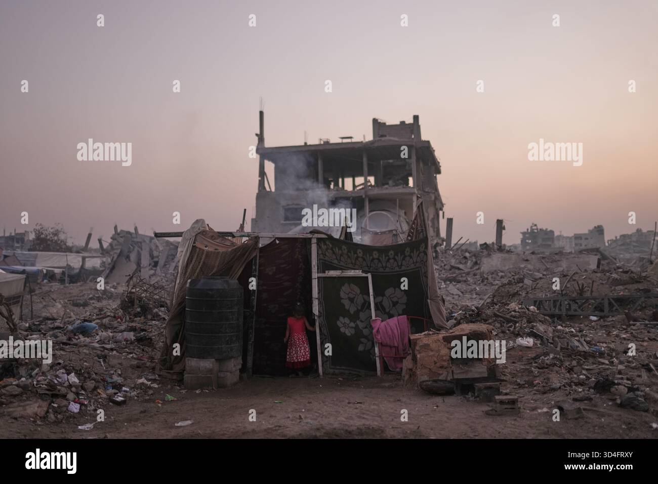 A displaced Palestinian girl stands at the entrance of her family tent ...