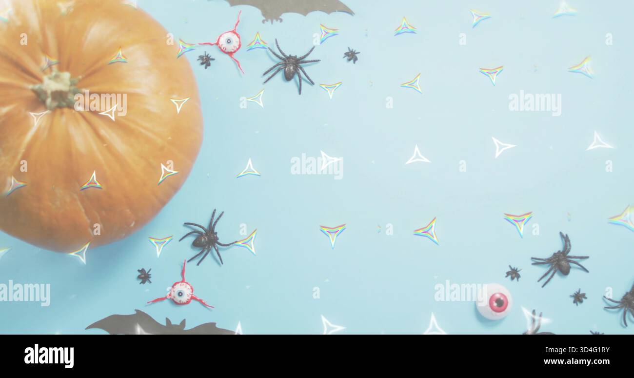 Positioning orange pumpkin left on pale-blue table scattering spiders eyeballs confetti, copy space Stock Photo
